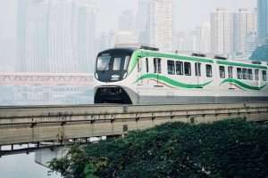 A green and white train on a bridge over water